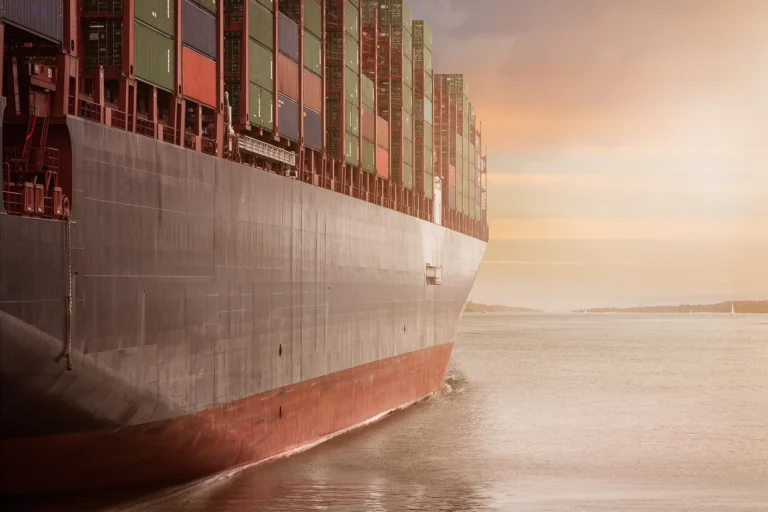 Large cargo ship loaded with colorful shipping containers, symbolizing global supply chain and offshoring.