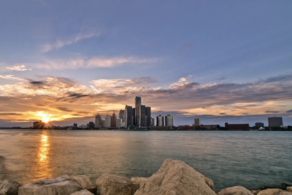 Detroit skyline at sunset with buildings reflecting on the river