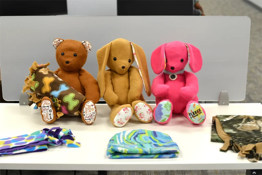 Handmade fleece stuffed animals, hats, and scarves created from Fleece & Thank You blanket scraps at Kinetyc, demonstrating adaptive manufacturing and zero-waste innovation.