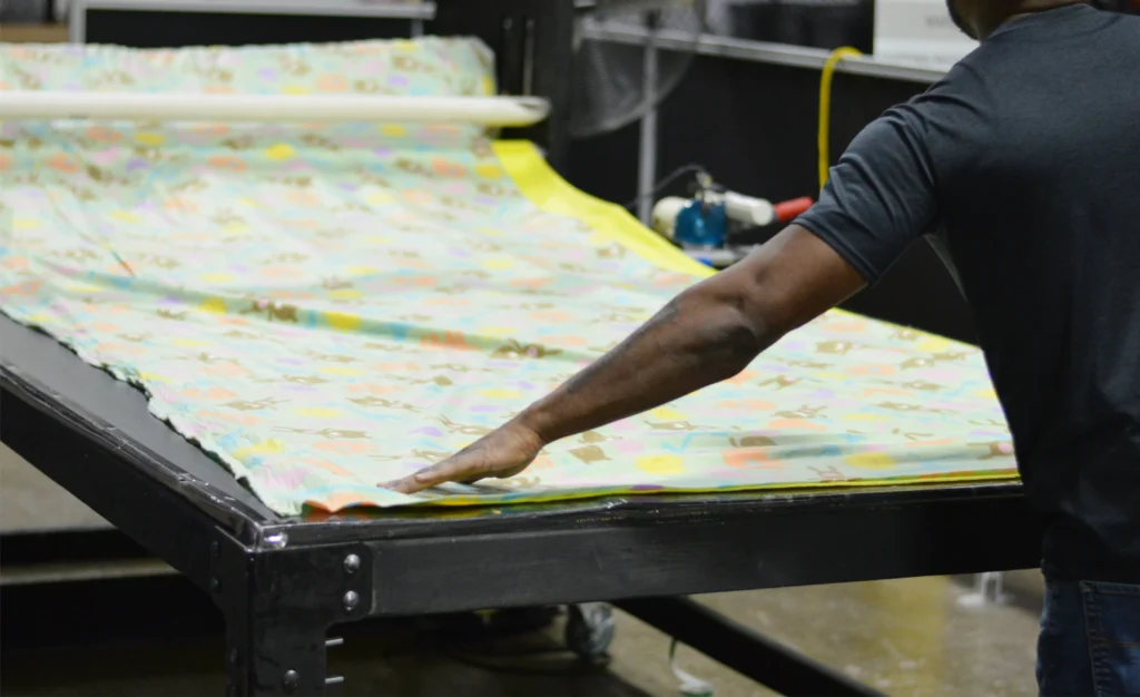 Kinetyc team member aligning layers of fleece fabric for Fleece & Thank You blanket production as part of a zero-waste adaptive manufacturing process.