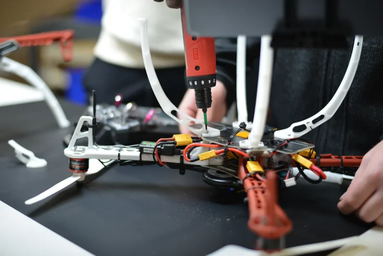 Close-up of drone assembly with electric screwdriver securing components and wiring