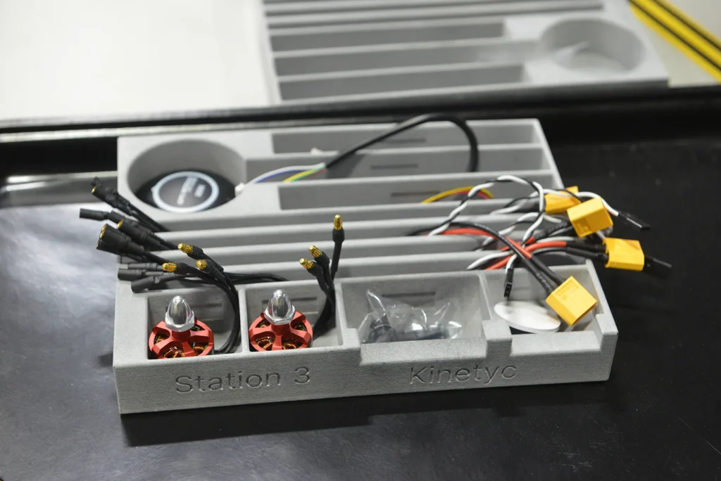Motors, wiring, and connectors organized in a compartmented assembly kit labeled Station 3 at Kinetyc.